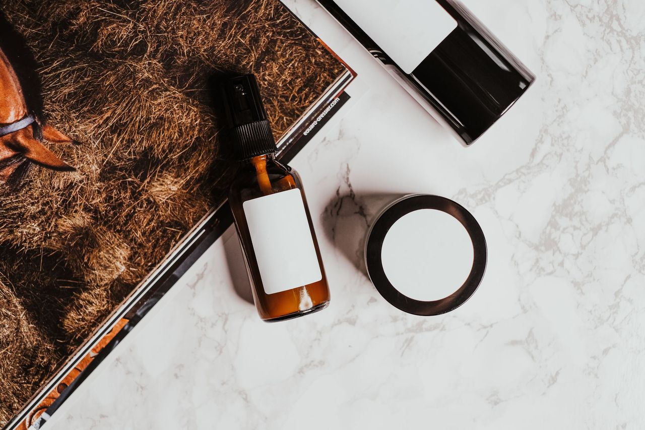 Serum bottle, cream jar and compact on a marble surface